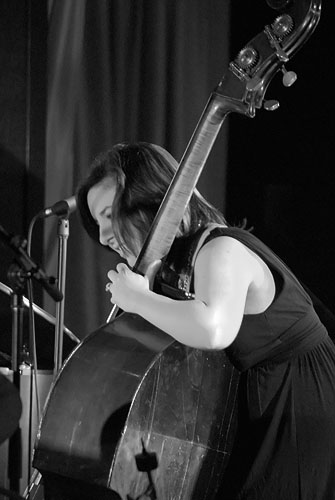 woman playing guitar on stage while wearing black dress
