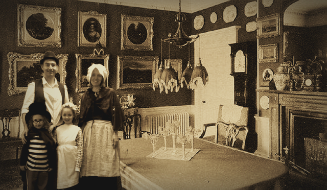 three adults and two children standing in a room decorated in ornate portraits