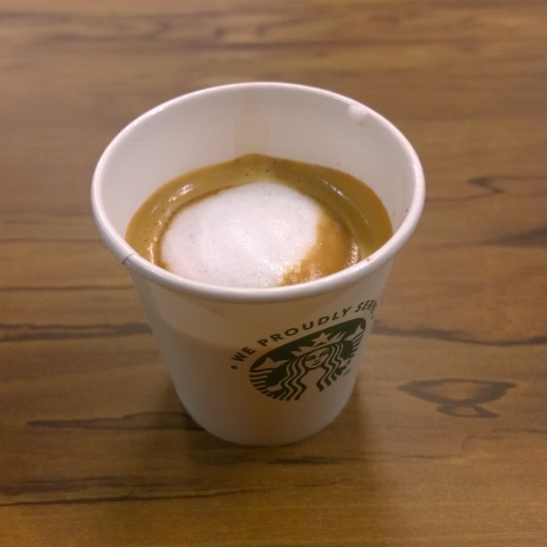 a small cup of beverage on top of a wooden table
