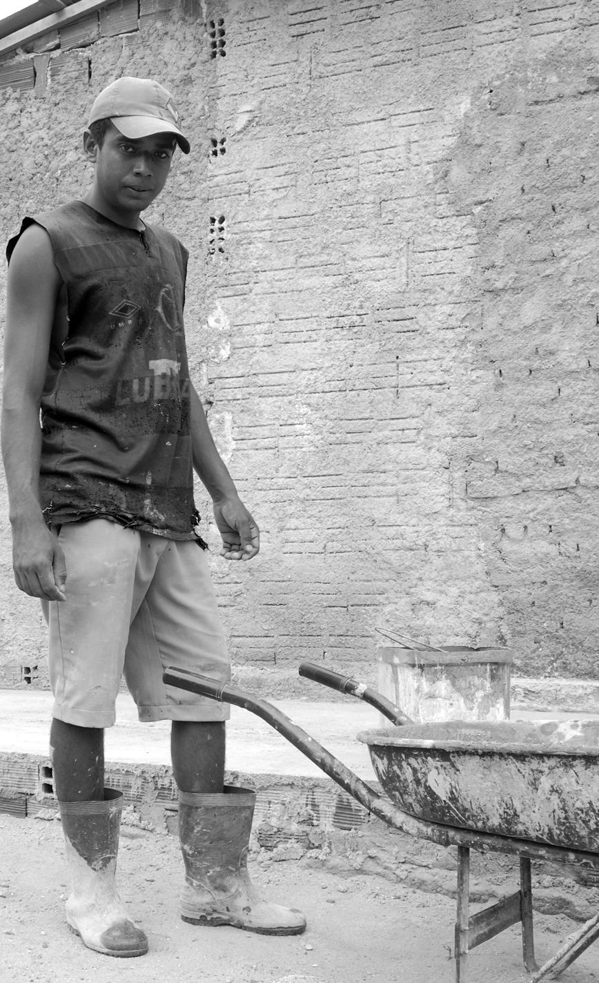 a man with a shovel standing in front of a wheel barrow