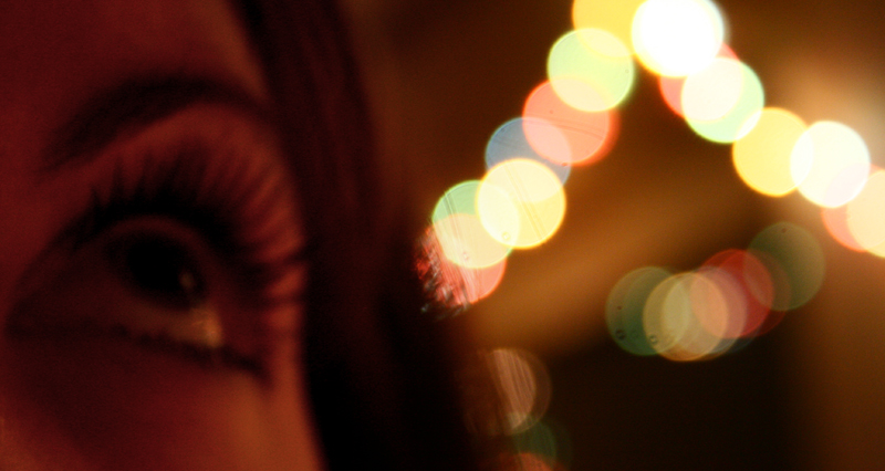 a close up of a womans eye with lights in the background