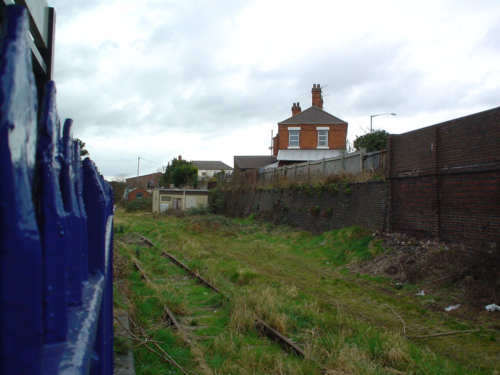 an abandoned train yard with a brick house in the background