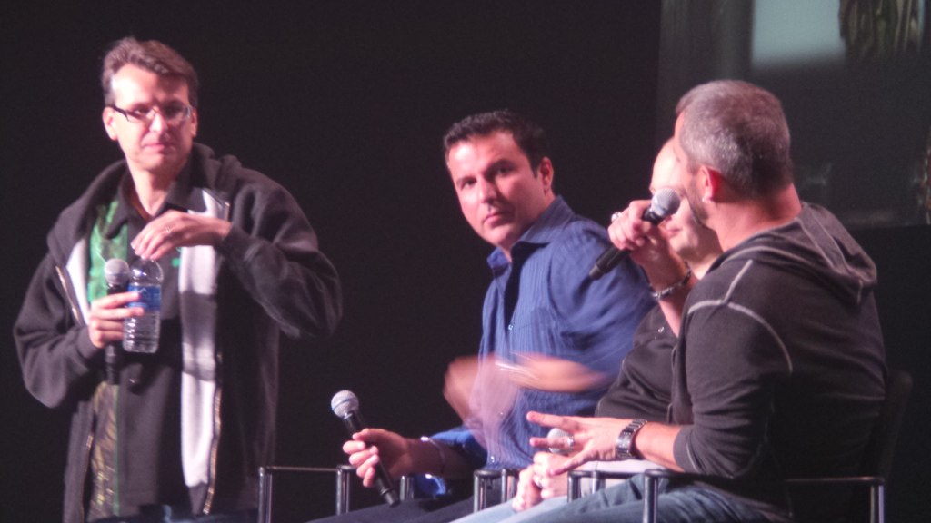 three men sitting in chairs and talking into microphones