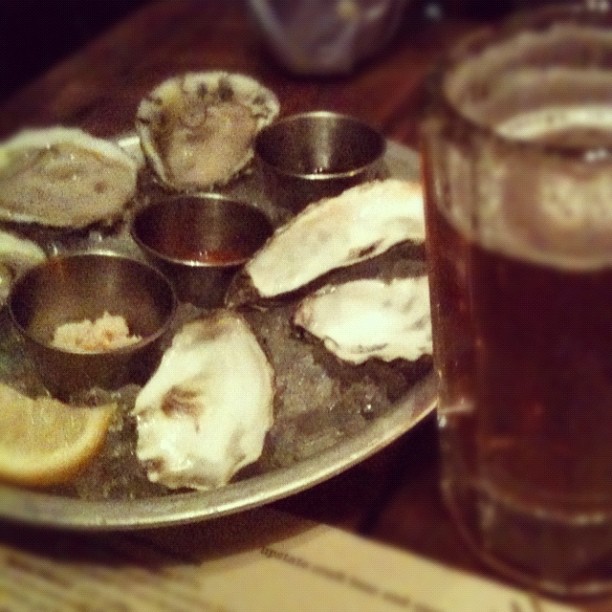 a plate full of oysters sitting next to a glass filled with beer