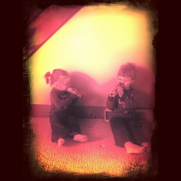 two children in front of a wall with a red light