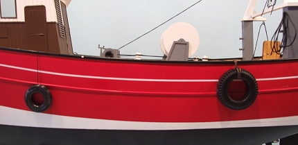 a red and black boat is shown floating on the water