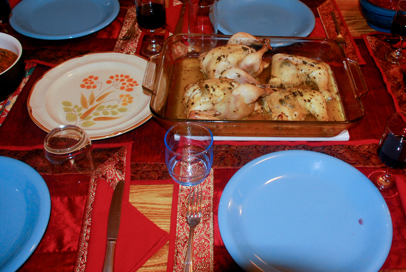 there is a large tray of chicken, sauces, silverware and plates on this table