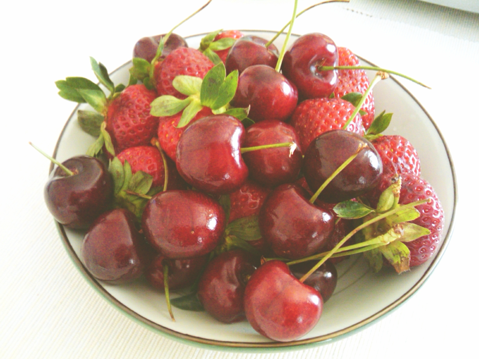 a close - up of a plate full of cherries and strawberries