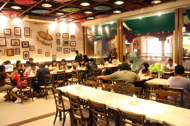 many people are sitting around eating inside a restaurant