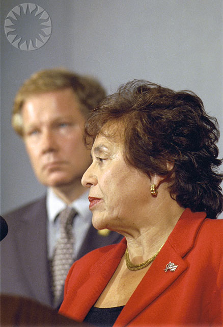 a woman sitting in front of a man with a microphone