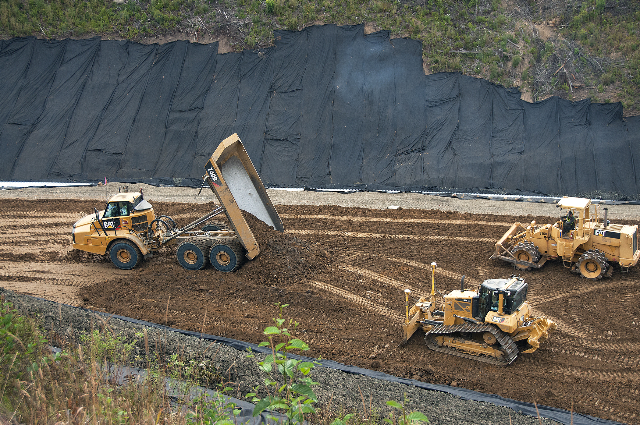 two large earth vehicles sitting in a dirt field