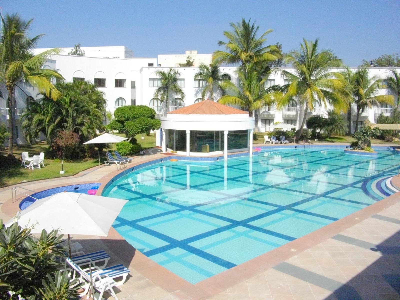 an empty swimming pool with lawn chairs and umbrellas