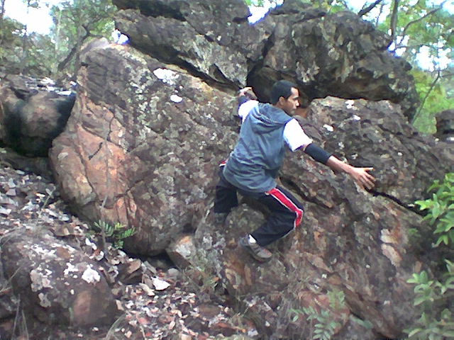 young man climbing on rock in the woods