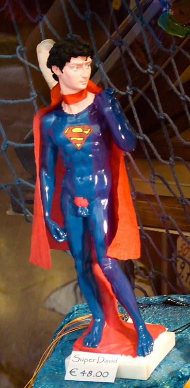 a batman statue in a blue suit holding a red cape