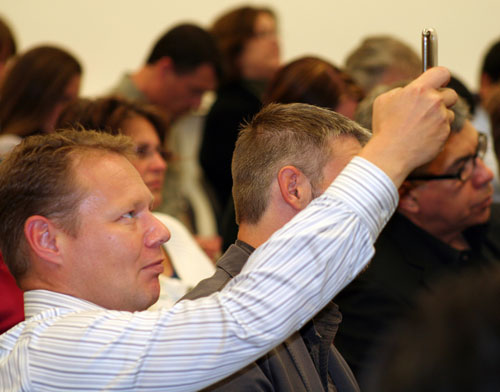 man taking po in front of audience with phone