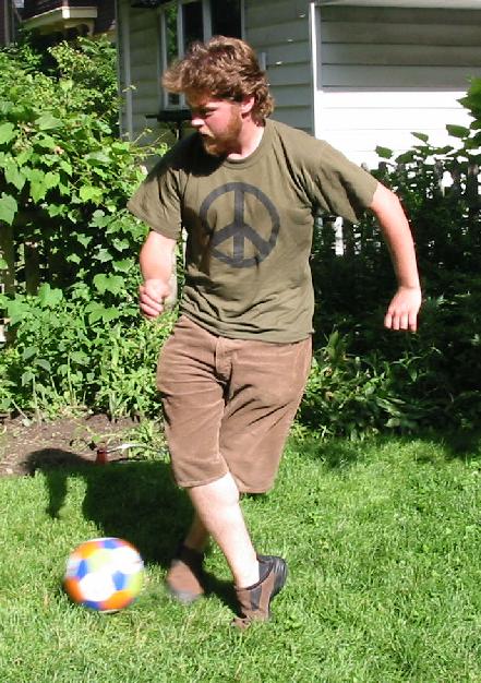 a man kicking a soccer ball in the yard