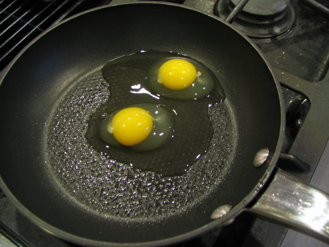 two eggs frying in oil in a set