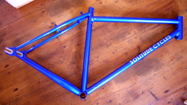 a blue bicycle frame laying on top of a wood floor