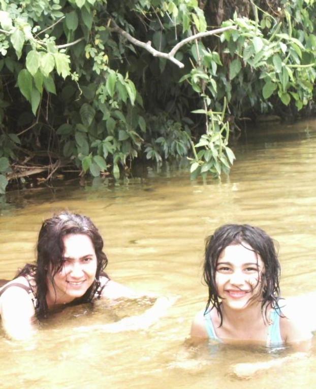 two girls float through muddy water in the jungle