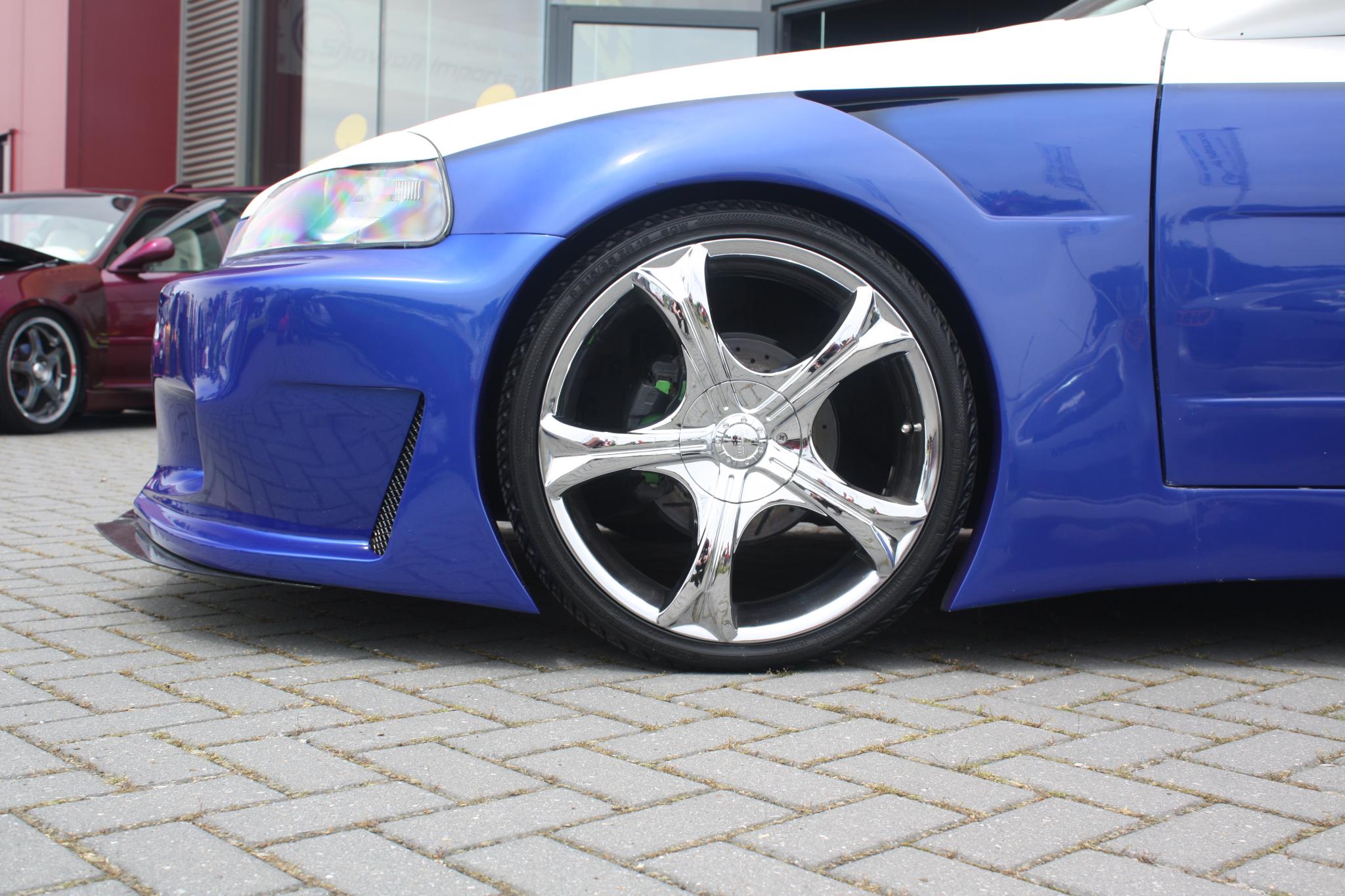 blue sports car parked in the driveway next to a red vehicle