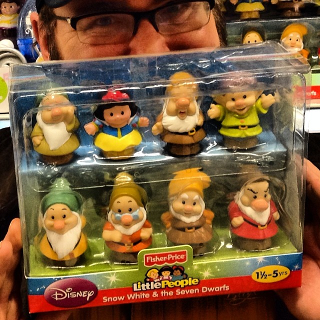 a man wearing a hat holding out snow white and the seven dwarfs