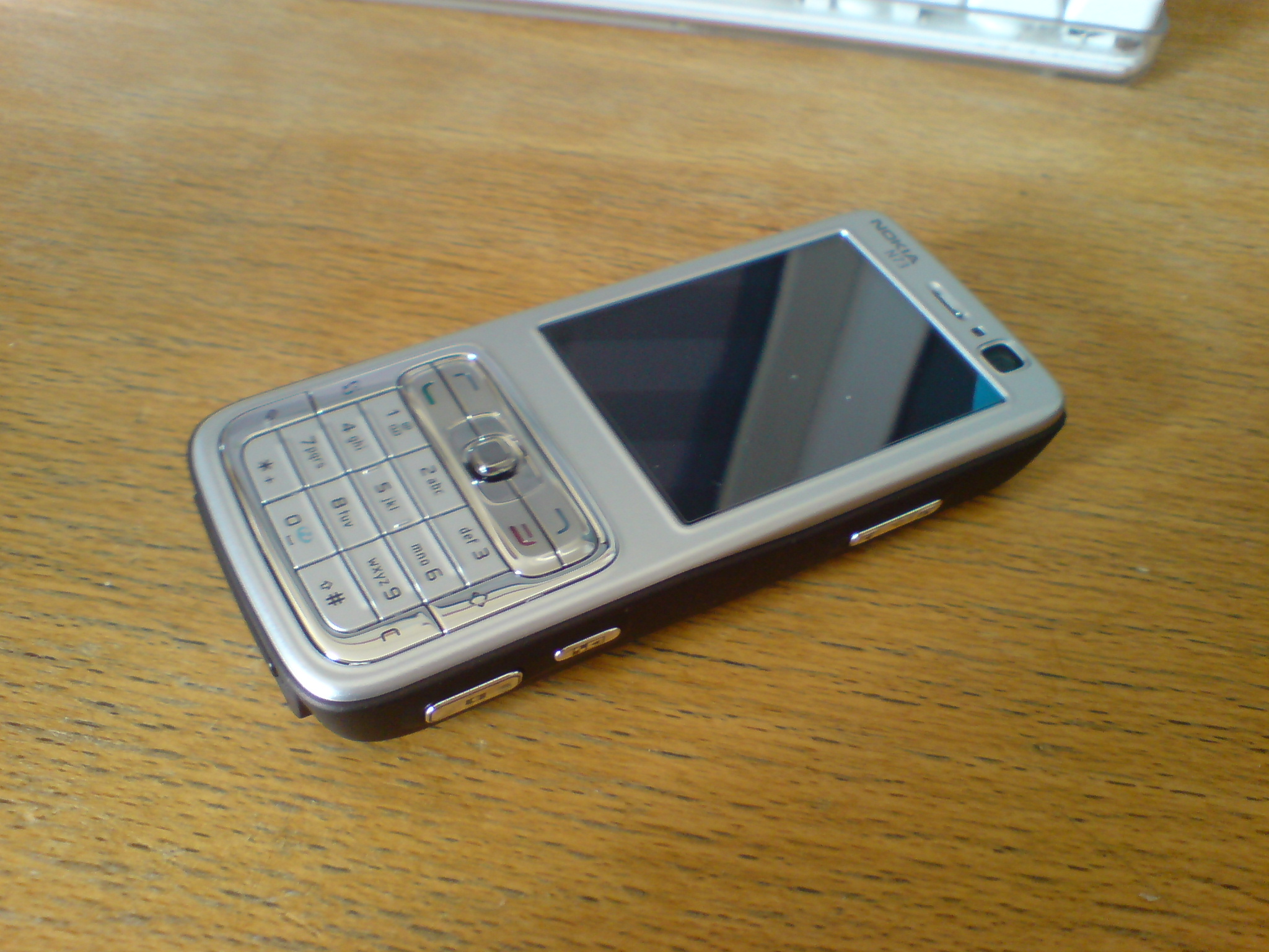 an old grey cellphone sitting on top of a wooden table