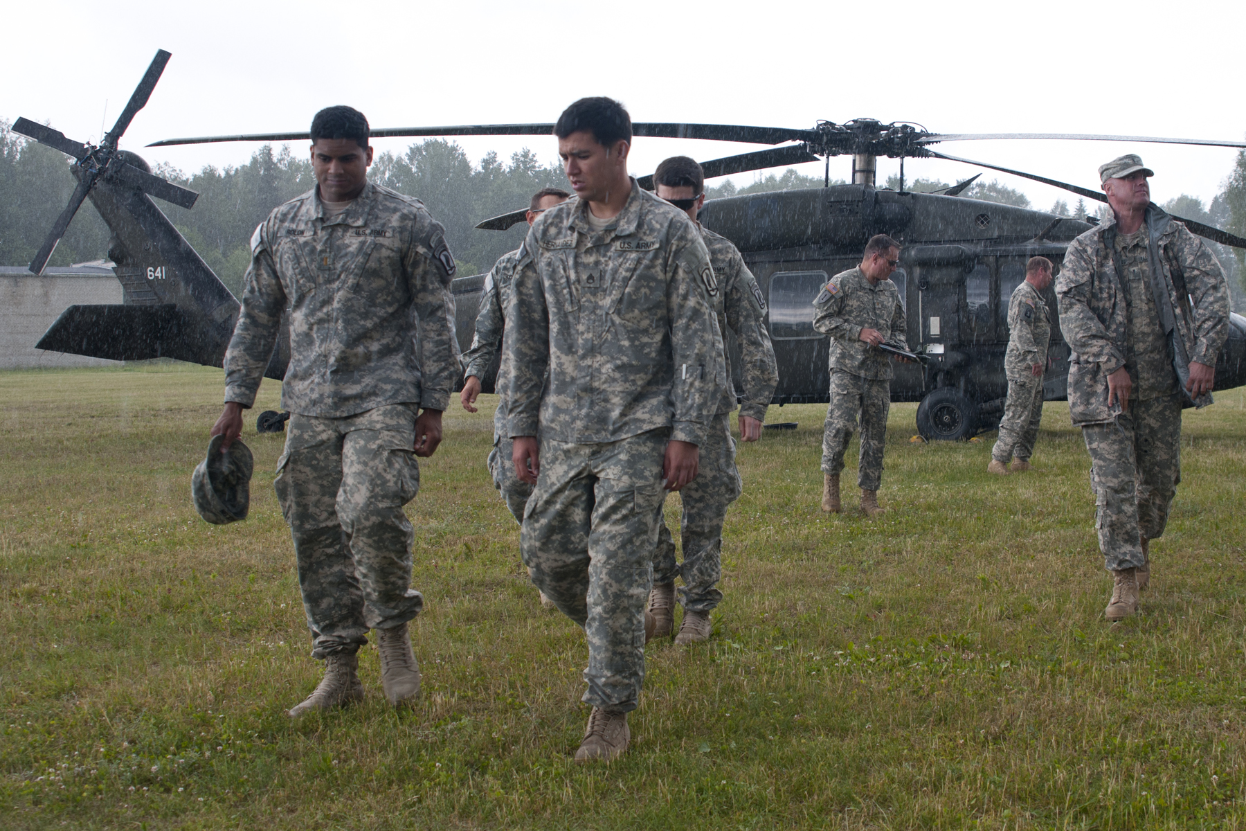 several soldiers walking in front of a helicopter