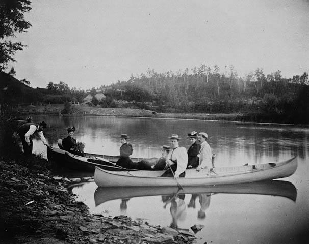 an old pograph of people in canoes on a river