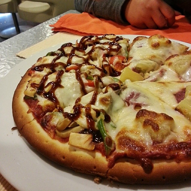 an uncut pizza with a cheese and vegetables topping