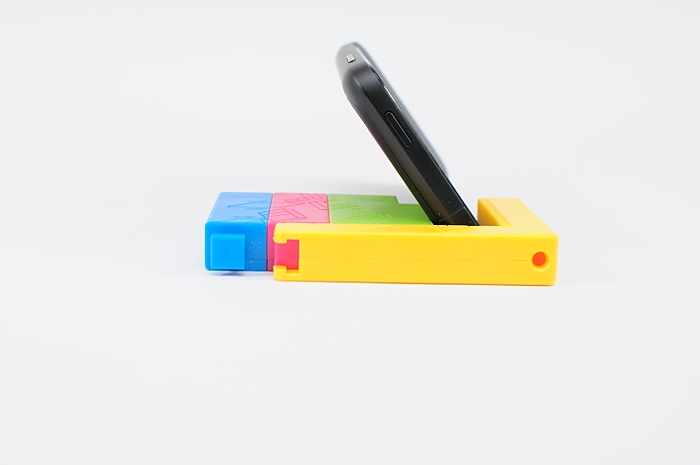 a flip - top cell phone resting on colorful block pen holder