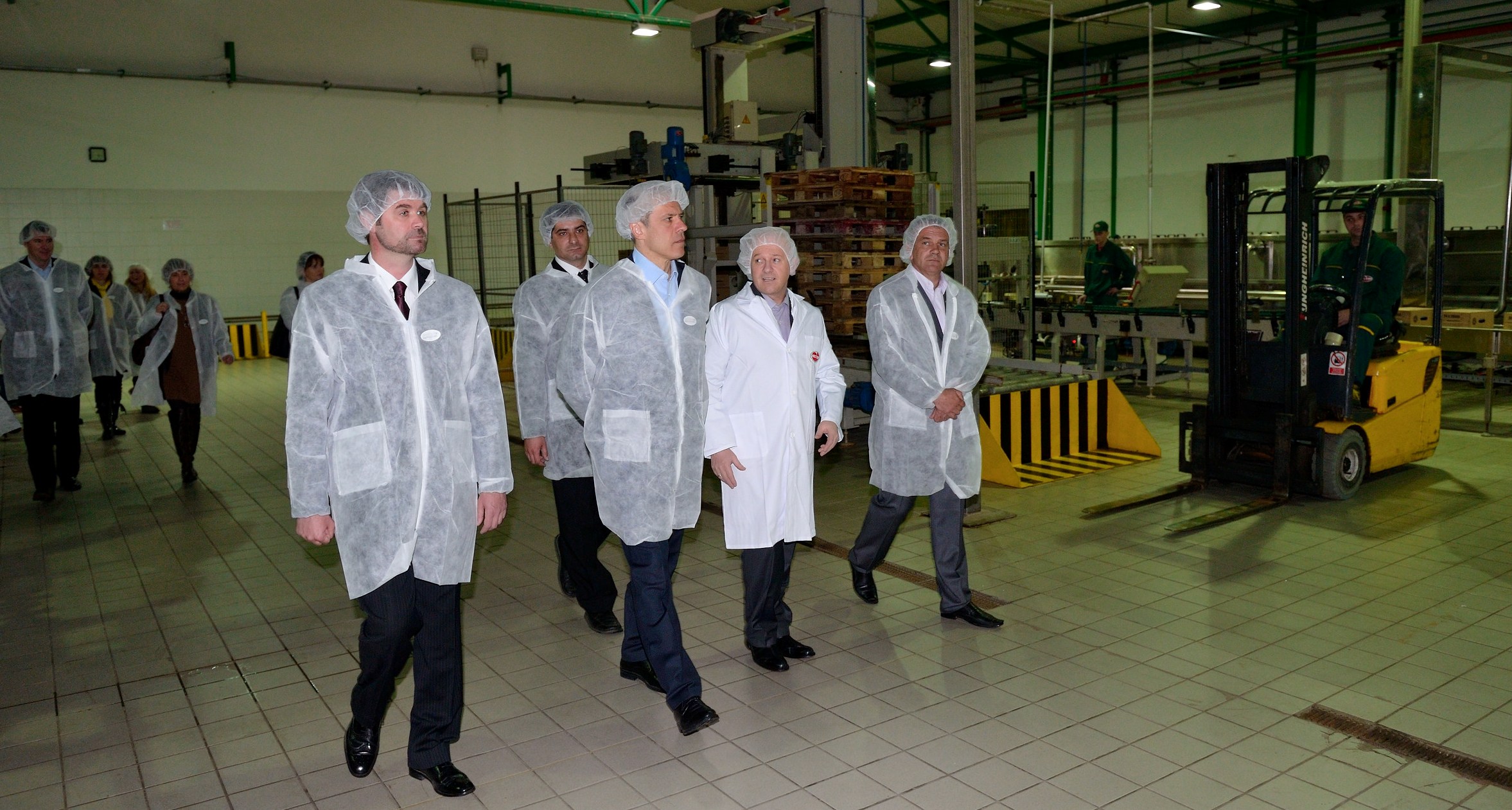 five people in lab coats walking together on a large floor