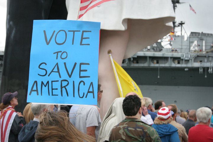 a large group of people with signs in front of a battleship