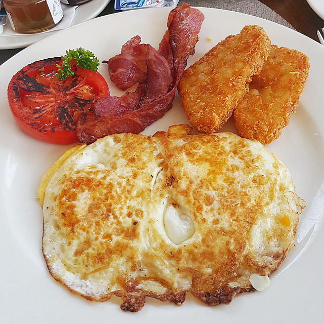 an egg omelet on a white plate with fried chicken and tomato slices