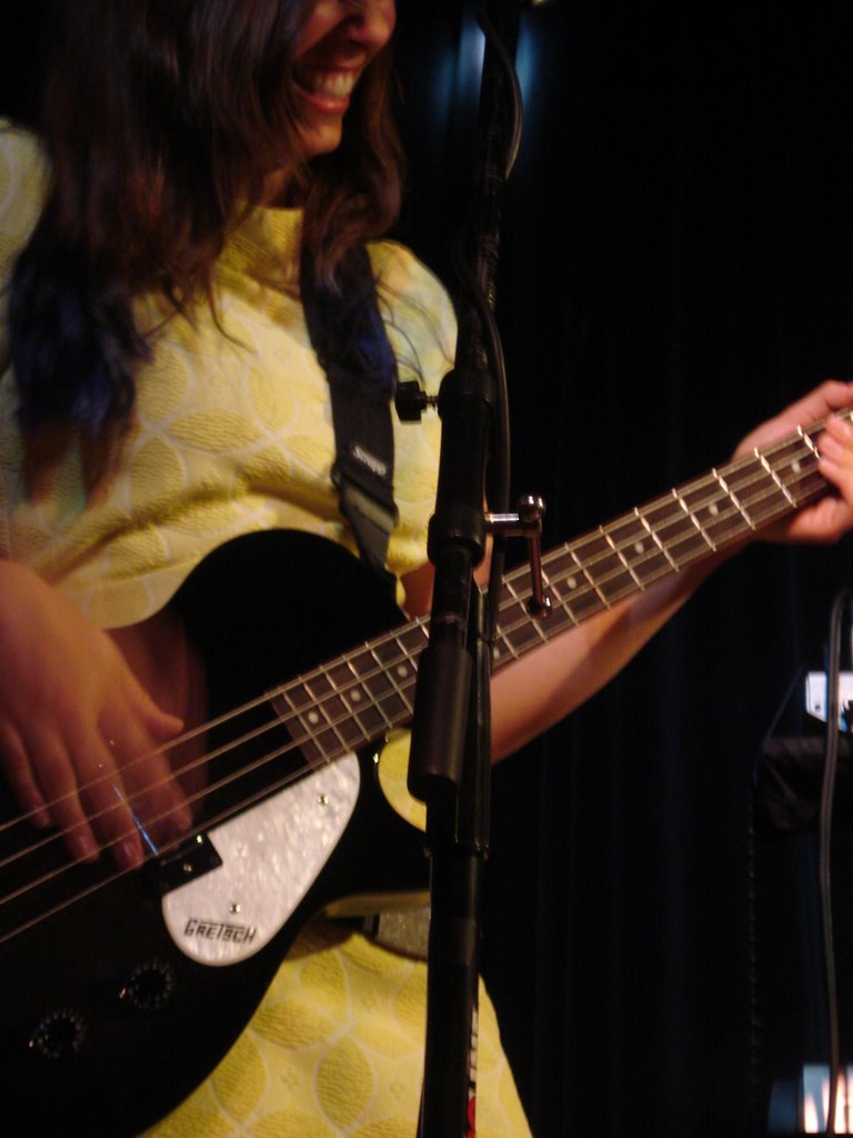 a woman plays a bass in front of a microphone