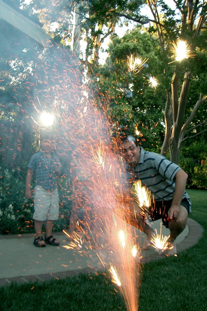 a man in shorts and grey shirt with sparkler behind him