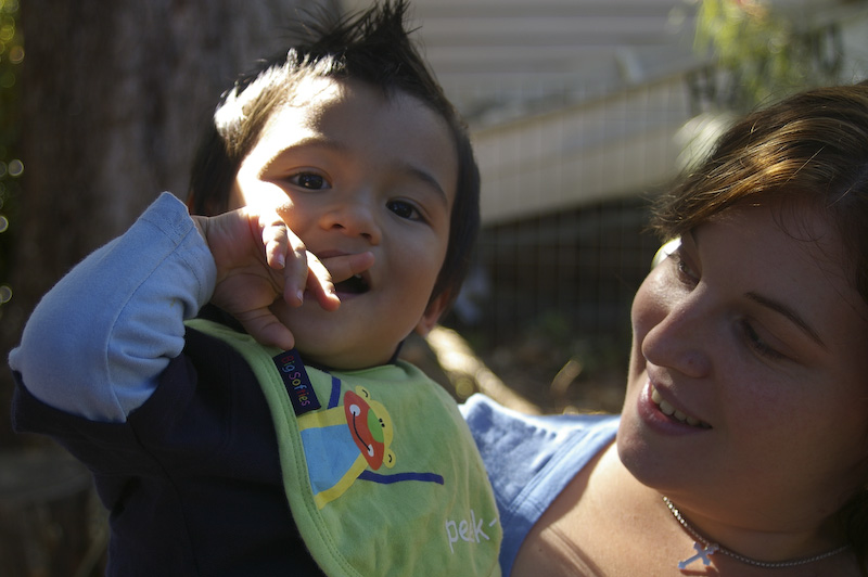 a woman holds a child's neck up with his thumb