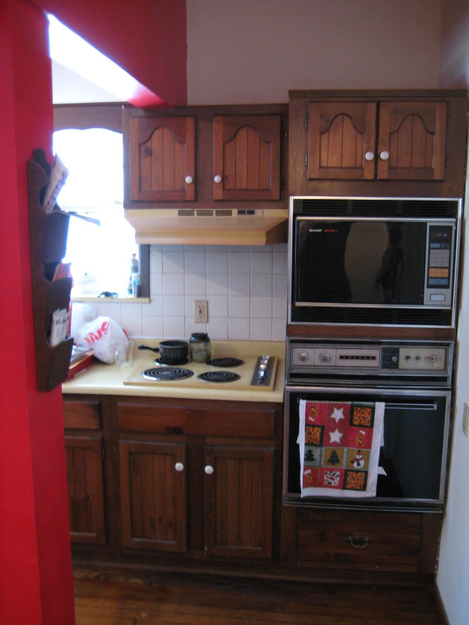 the inside of a kitchen with oven, counter top and cabinets