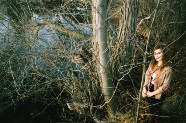 a woman standing next to a tree on a river