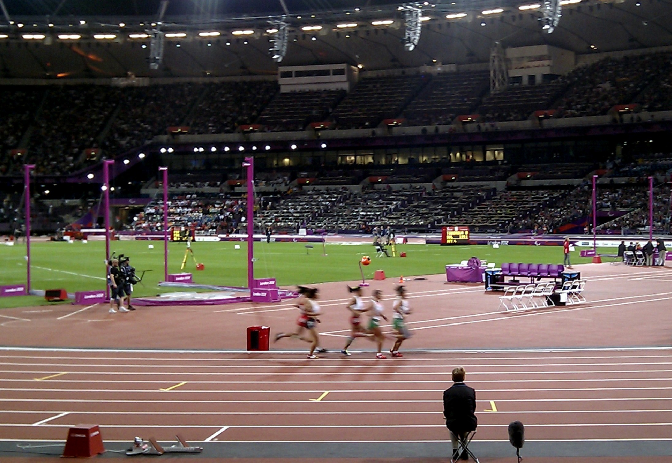 many people are running across a track in an arena