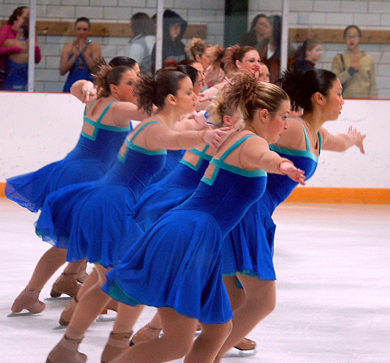 group of women in blue dresses performing a routine on the ice