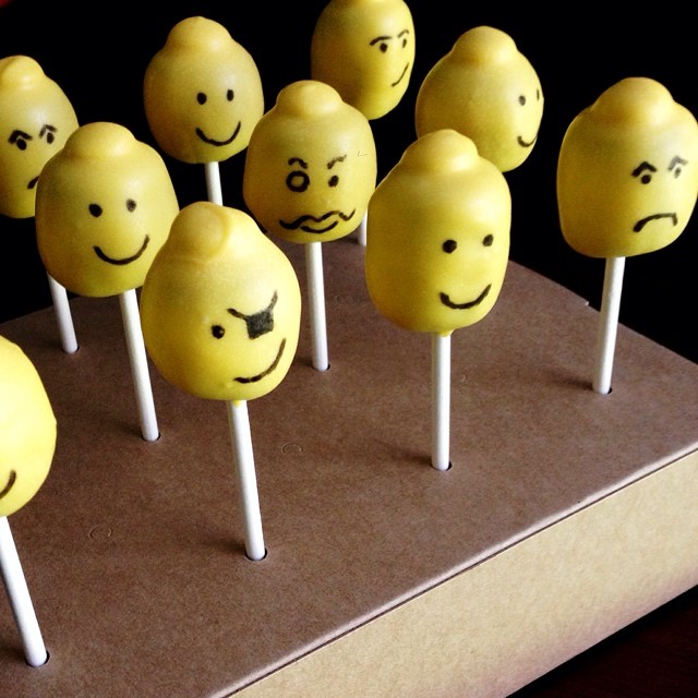 a bunch of yellow lollipops with faces painted on them