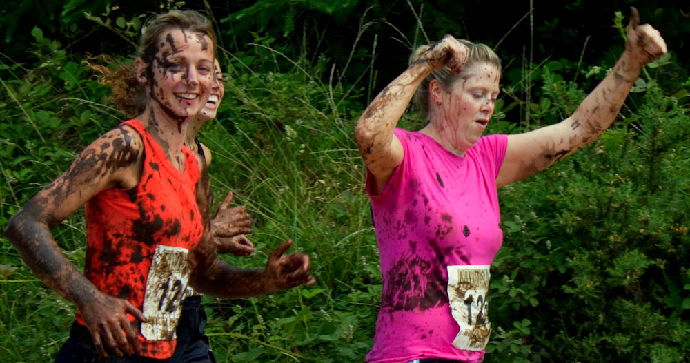 two people covered in mud and paint running