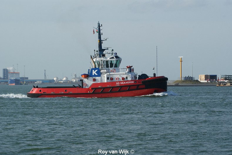 a red and white tugboat on water near buildings