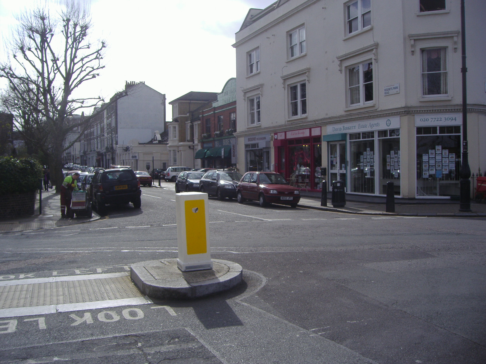 the street with yellow painted post is filled with parked cars