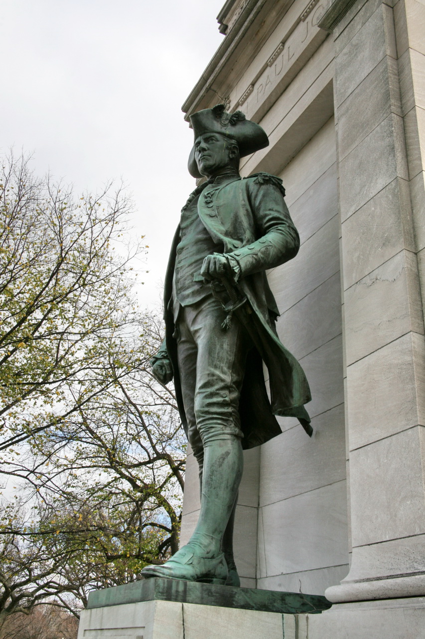 statue in front of grey and stone building with trees in the background