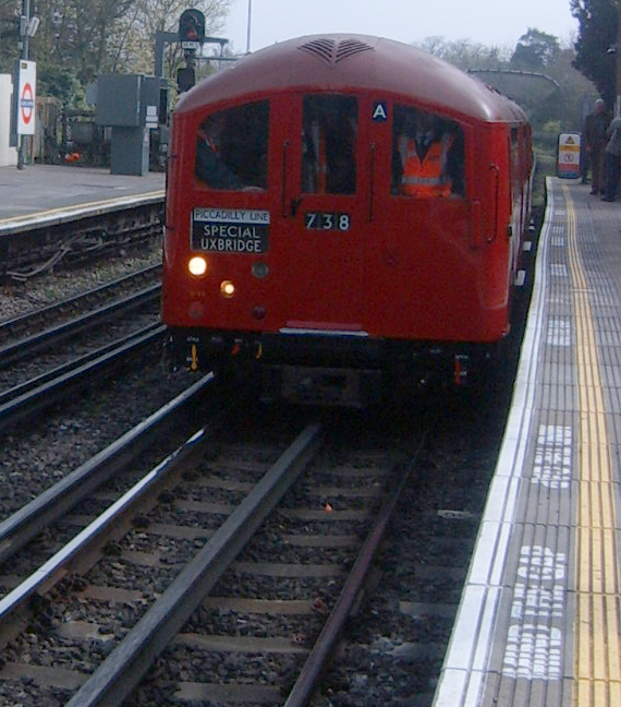 red train with two people on the front drives down the tracks