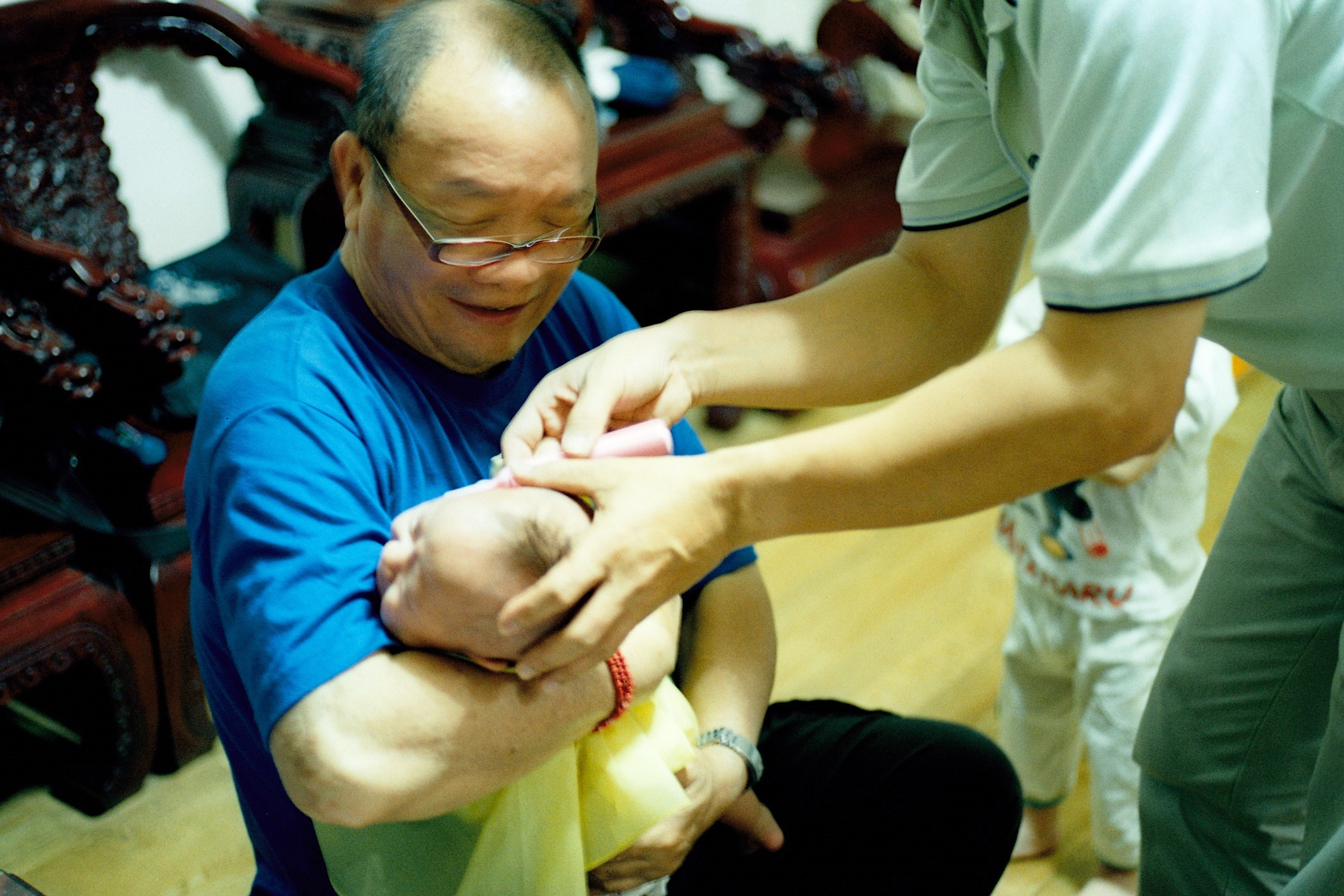 a man in blue shirt holding baby on wooden floor