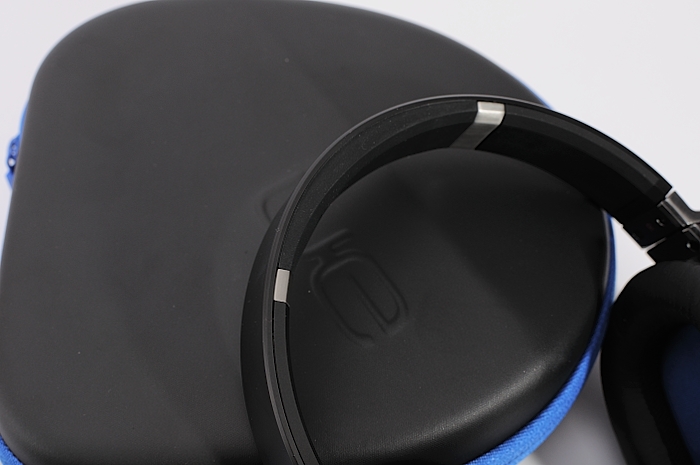 black headphones resting on blue surface next to white background