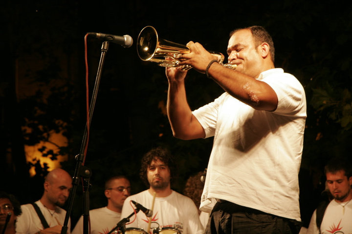 a man playing the trumpet while his band is singing