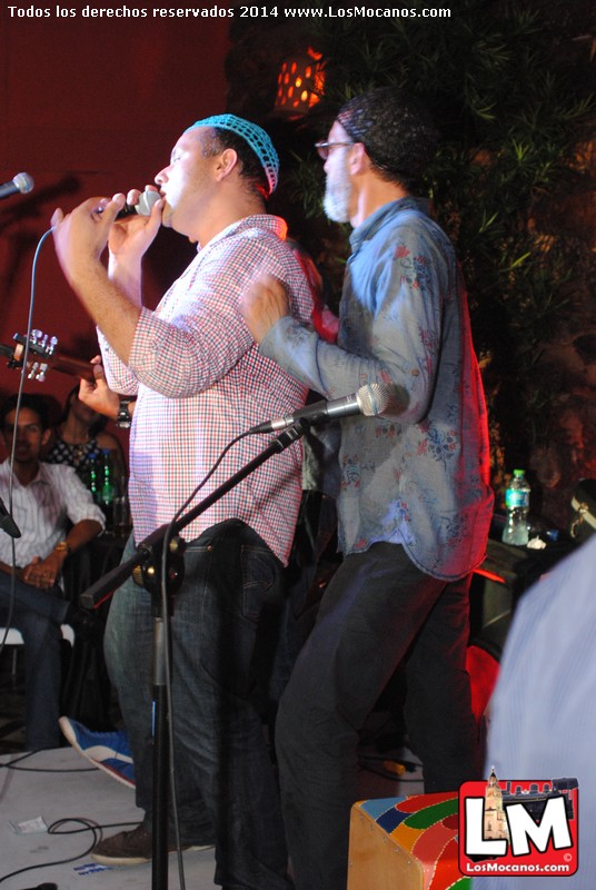 two men standing on stage and singing into microphones